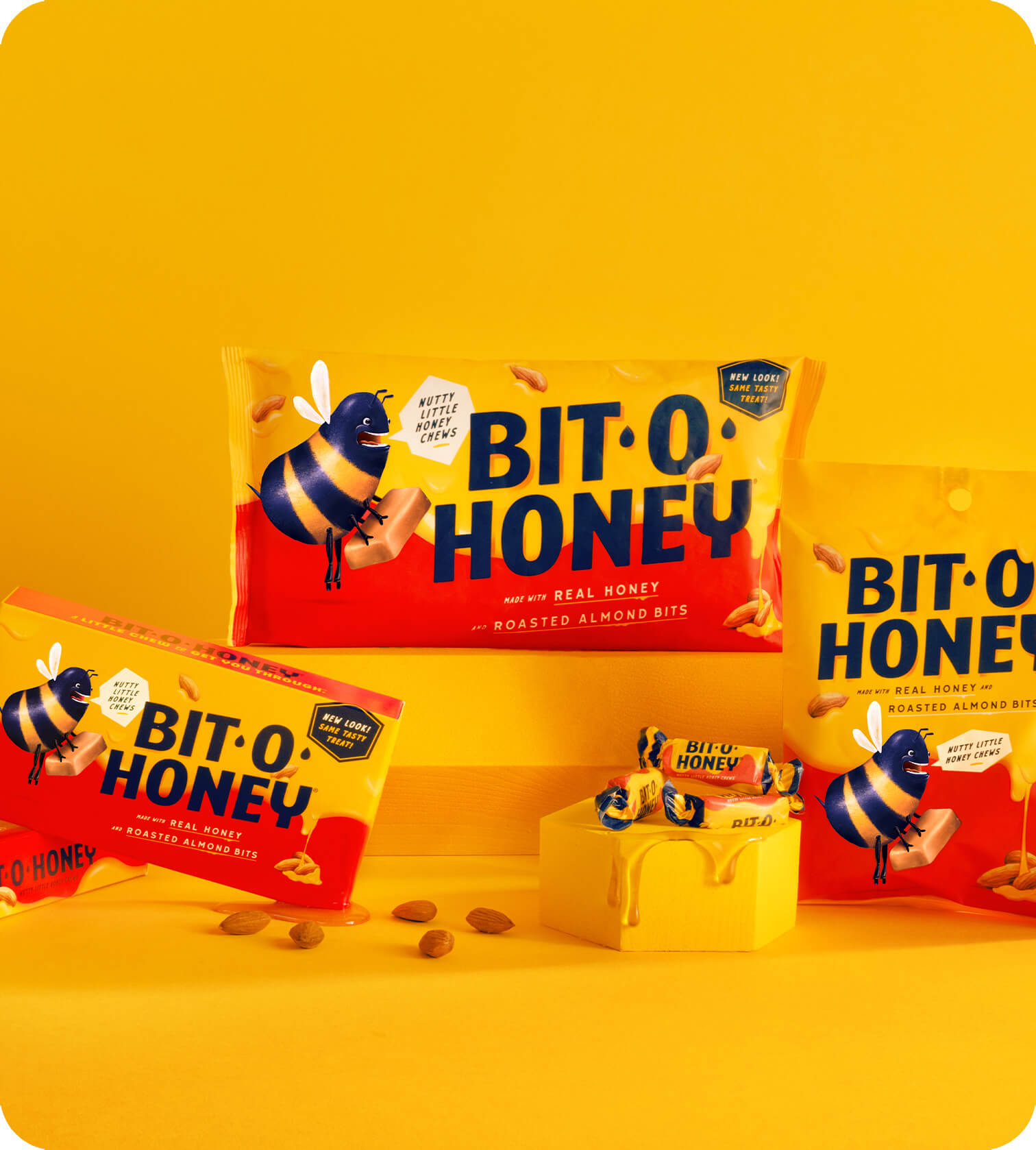 Family shot of Bit-O-Honey’s packaging in front of a blue sky, surrounded by honey and almonds